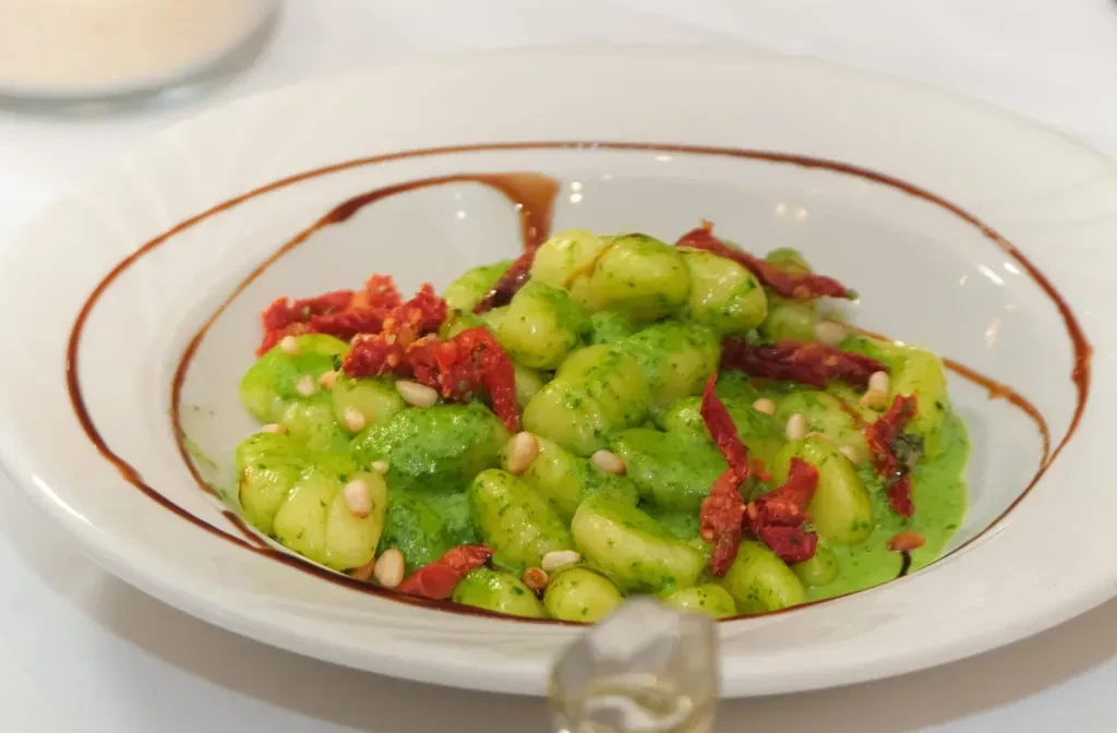 Gnocchi with green pesto, sun-dried tomatoes, and pine nuts.