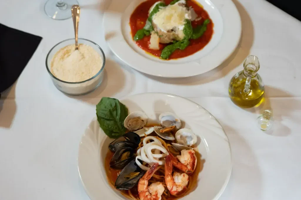 Restaurant table with seafood spaghetti and a baked pasta dish.