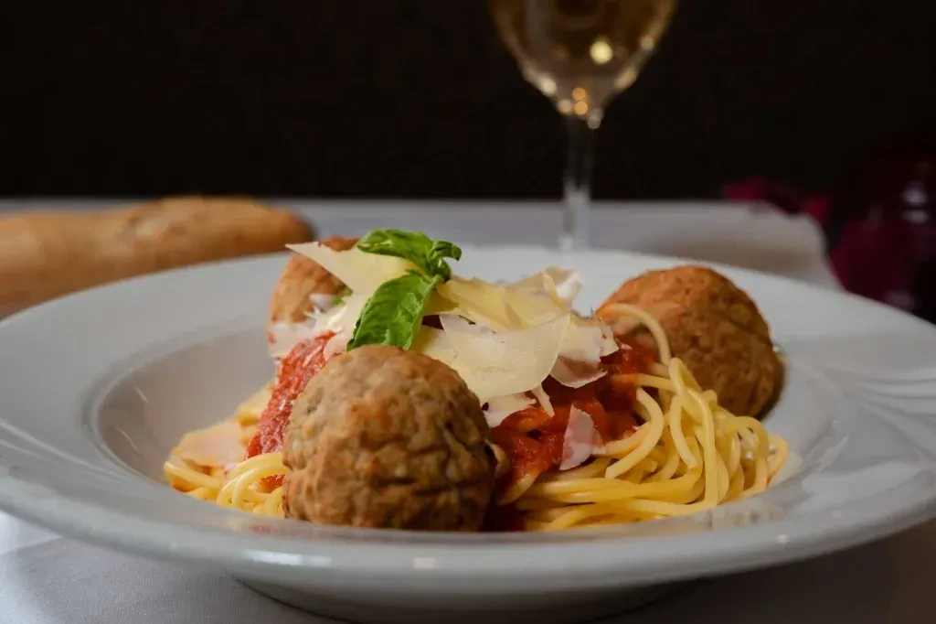 Plate of spaghetti and meatballs with tomato sauce, Parmesan, and basil.