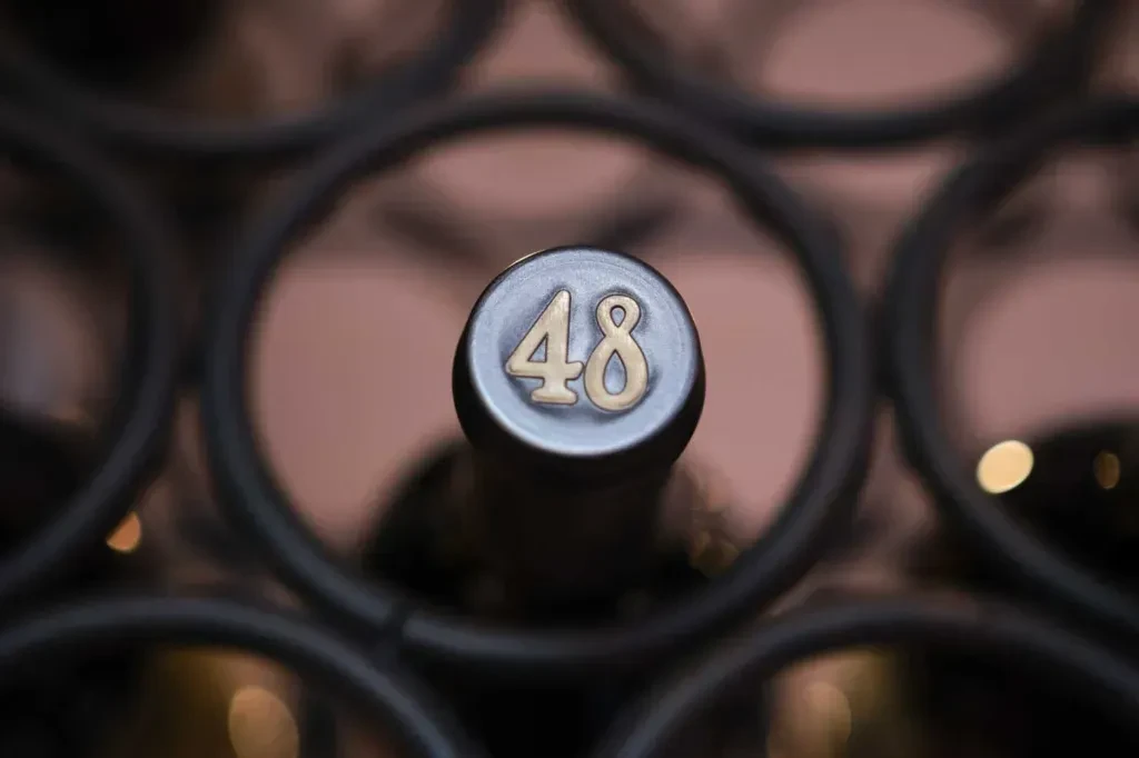 Dark wine bottle top with embossed golden number 48 in a rack.