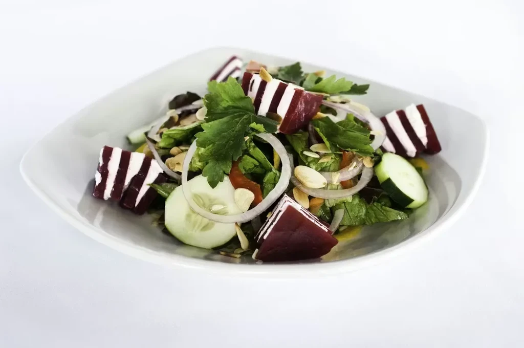 Fresh salad with lettuce, cucumber, beets, onion, almonds, and parsley.