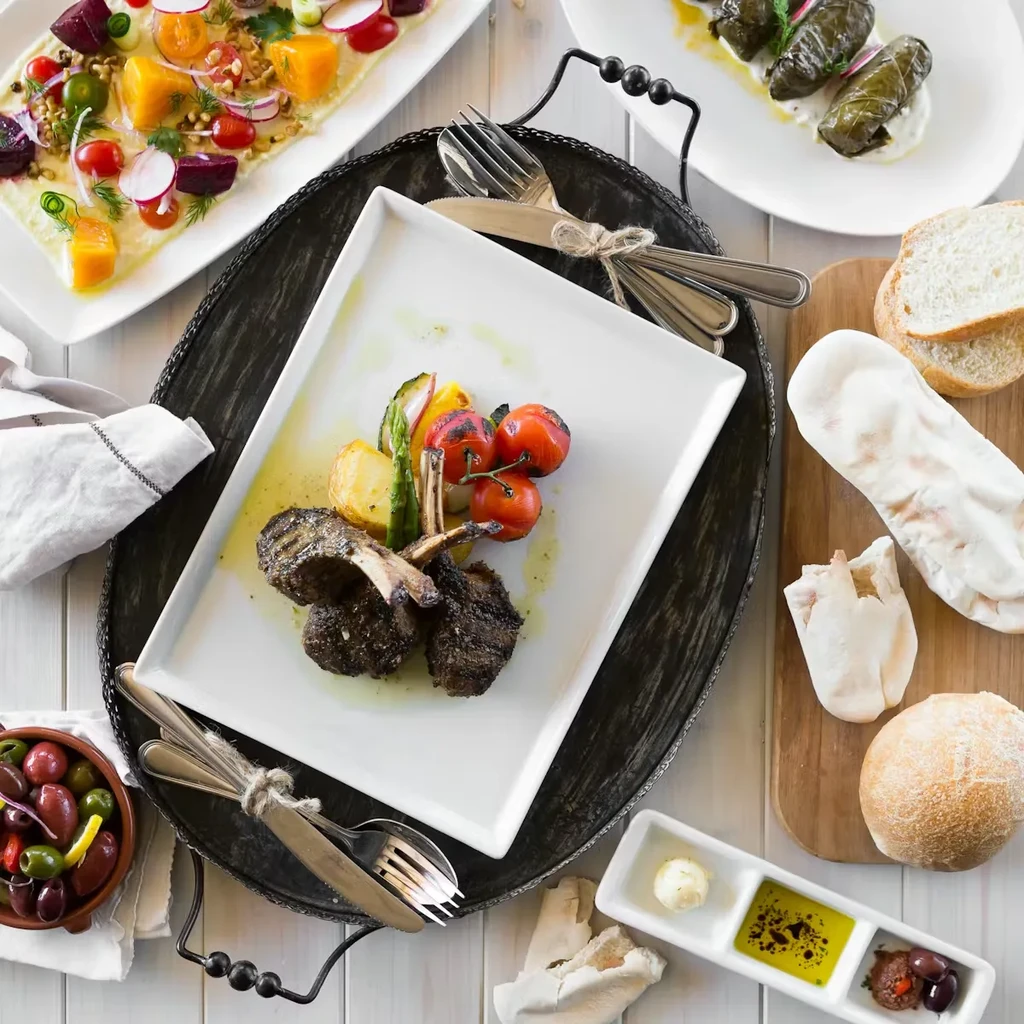 Meticulously plated lamb chops, vegetables, and a spread of Mediterranean dishes.