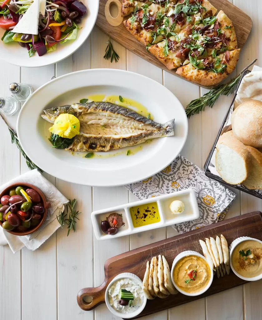 Overhead: Diverse Mediterranean dishes including grilled fish, salads, and dips.