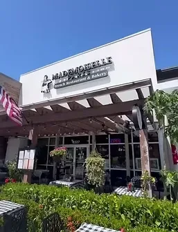 Mademoiselle de Paris French restaurant exterior with outdoor patio and flag.