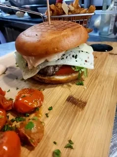 Gourmet burger with melted cheese, roasted tomatoes, and fries.