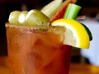 Heavily garnished Bloody Mary cocktail with celery, olives, lemon, and seasoned rim.