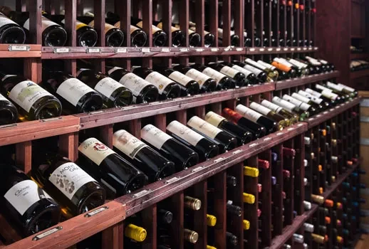 Rows of wine bottles neatly arranged in dark wooden racks.