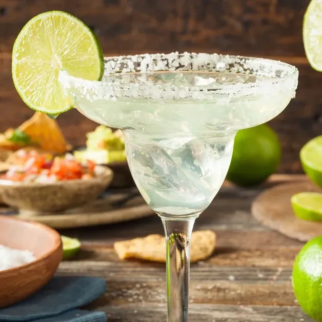 Salt-rimmed margarita with lime and ice, with chips and salsa.