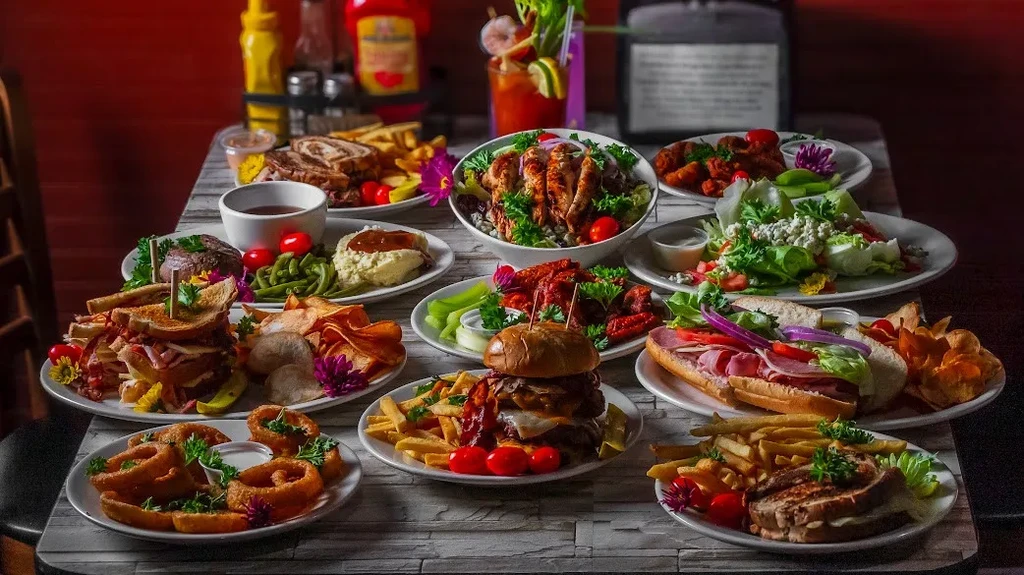 Vibrant spread of diverse restaurant dishes, drinks, and condiments on a table.