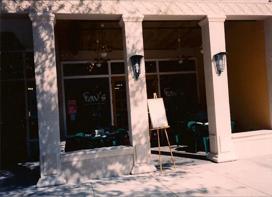 Fav's restaurant facade with columns, glass windows, and sidewalk easel.