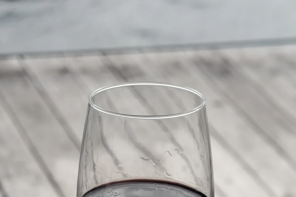 Close-up of red wine in a glass on a blurred wooden surface.