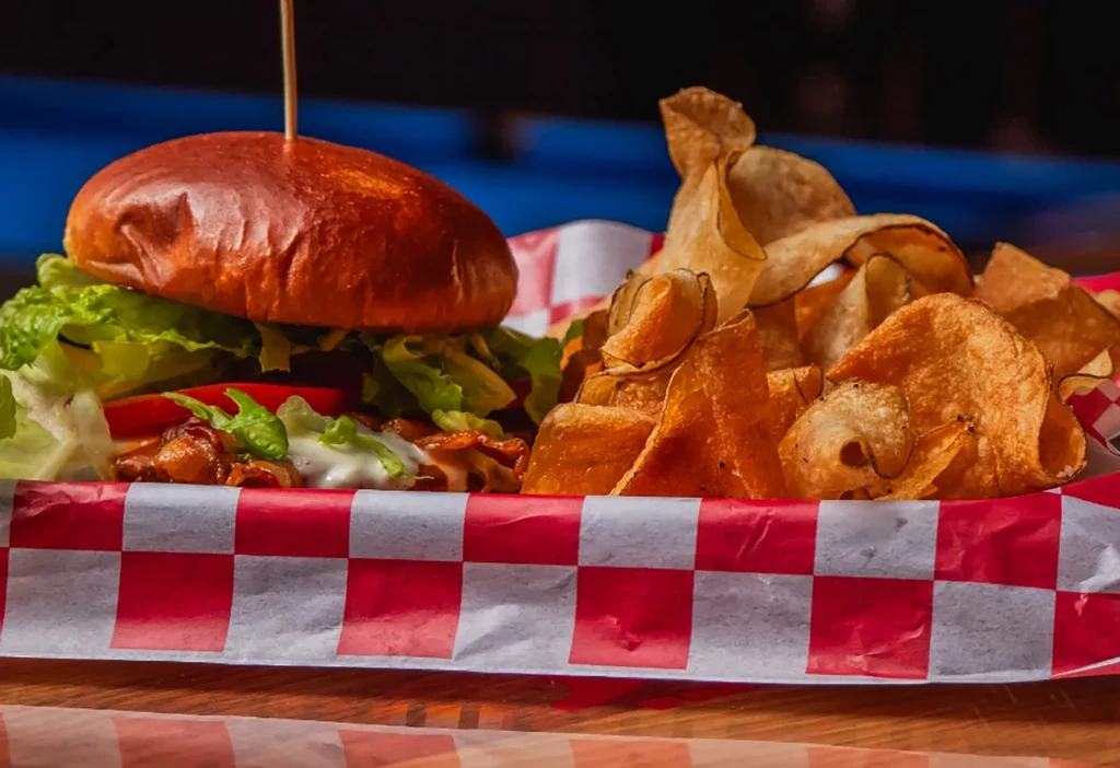 Close-up of a gourmet burger and wavy potato chips in a checkered basket.