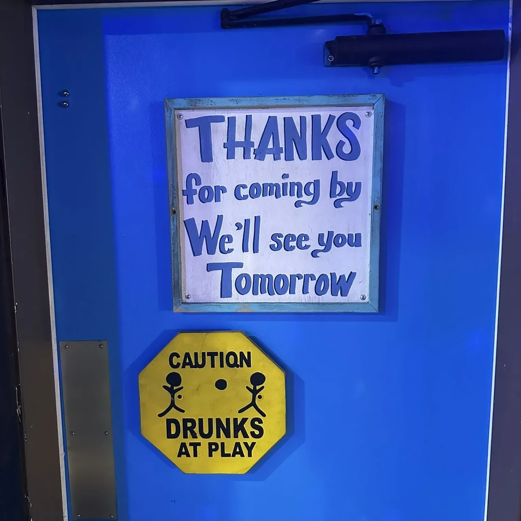 Blue door displaying 'Thanks for coming' and 'CAUTION DRUNKS AT PLAY' signs.