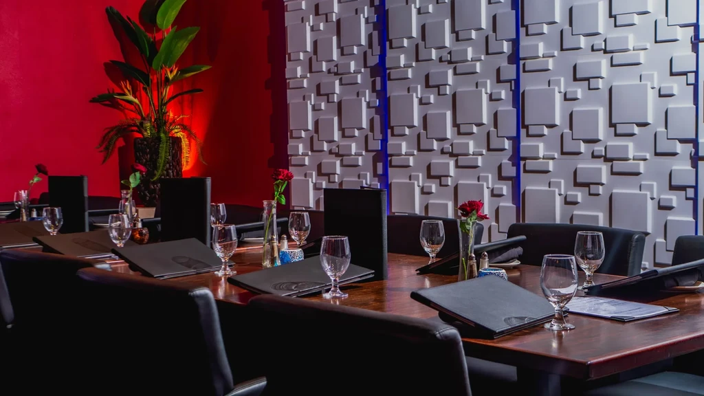 Restaurant private dining room: long wooden table, black chairs, dual-textured walls.