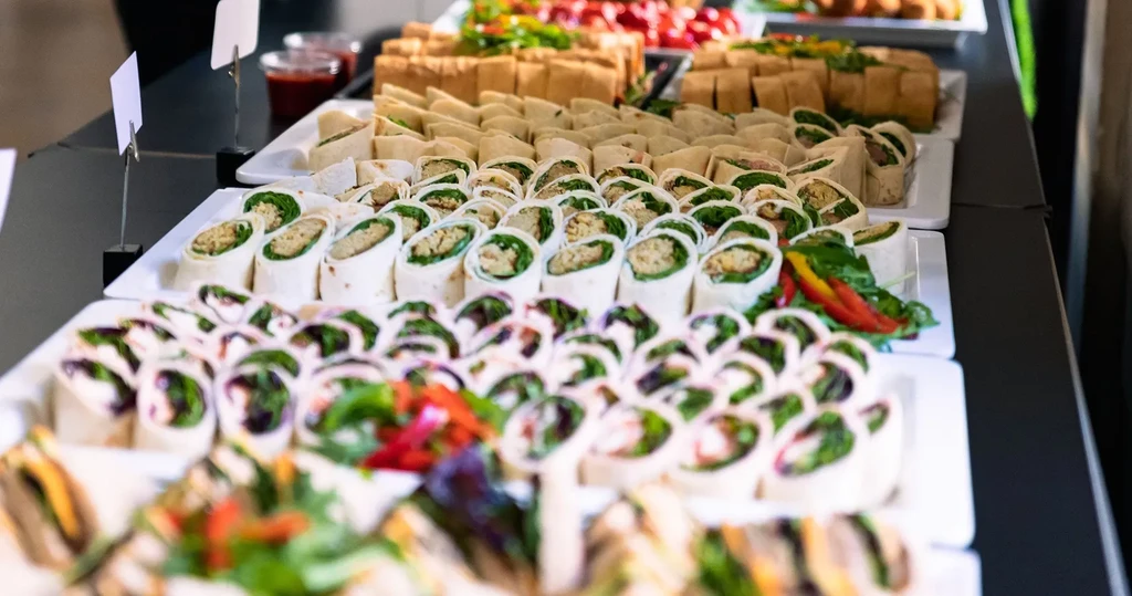 Neatly arranged colorful wrap halves and small items on buffet platters.