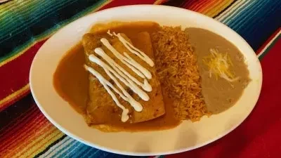 Overhead shot: Burrito or enchilada with rice, beans, on a striped serape.