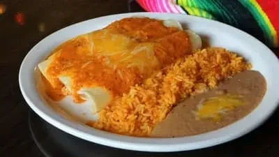 Two enchiladas covered in red sauce and cheese with rice and beans.