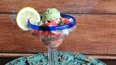 Colorful appetizer in a blue-rimmed glass with guacamole and lemon.