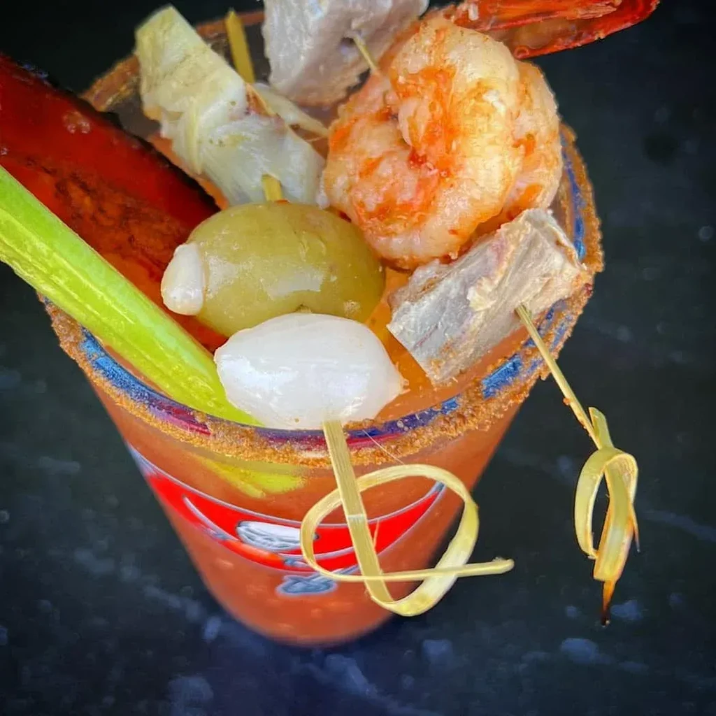 Bloody Mary cocktail generously garnished with shrimp, bacon, olive, and celery.