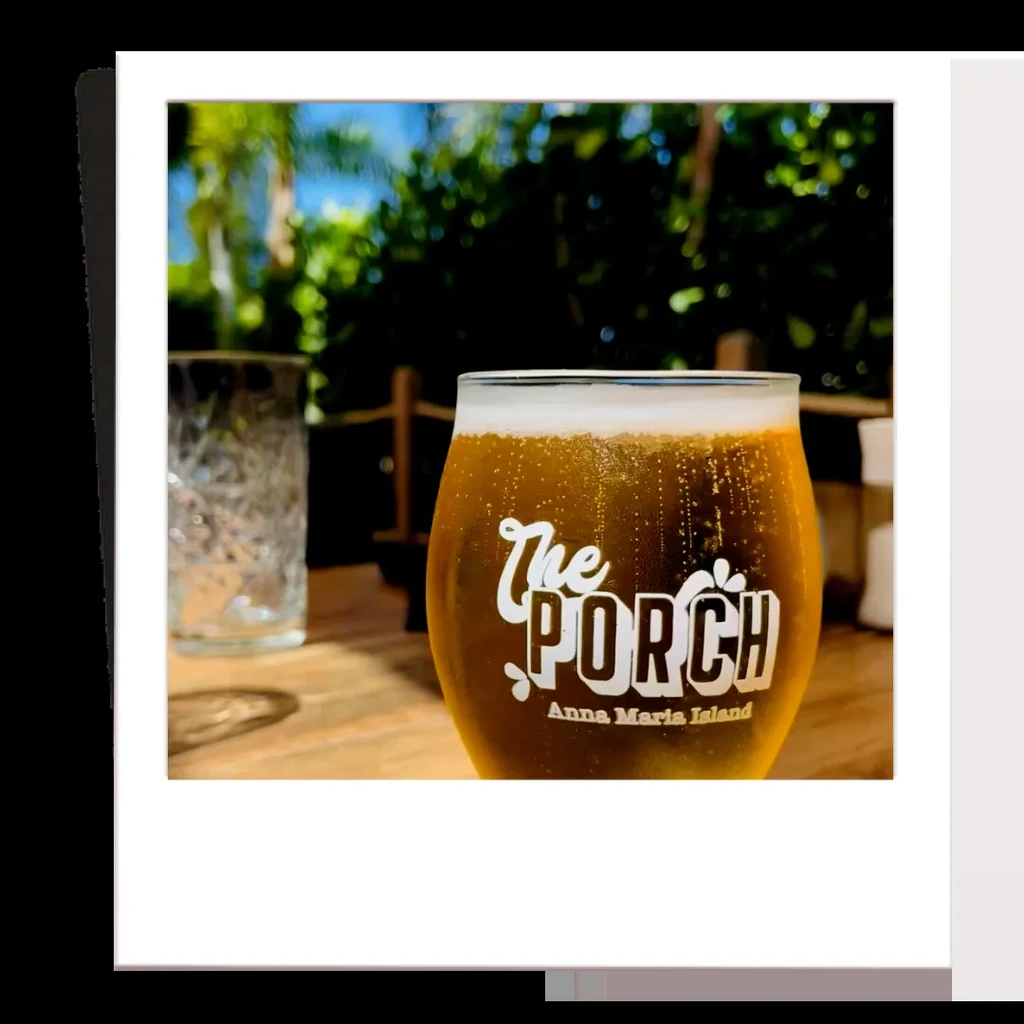 Amber beer in a branded "The PORCH" glass on an outdoor table.