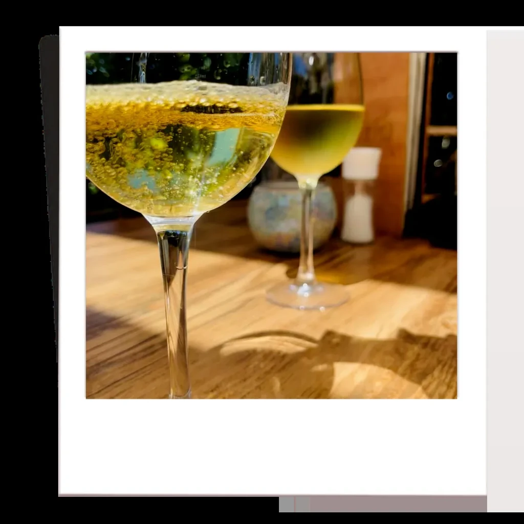 Two wine glasses with sparkling golden drinks on a wooden table.