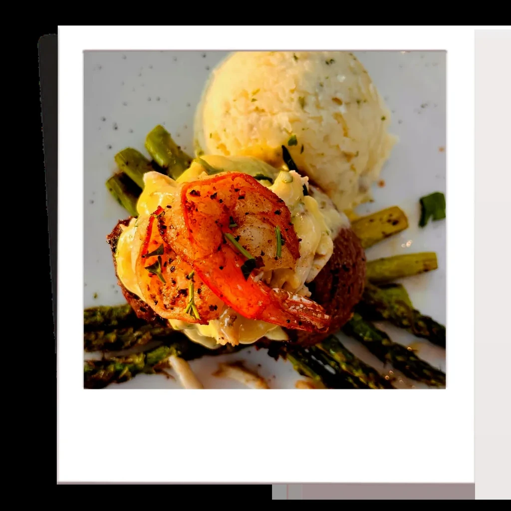 Plated meal of shrimp, creamy sauce, and asparagus on a white plate.