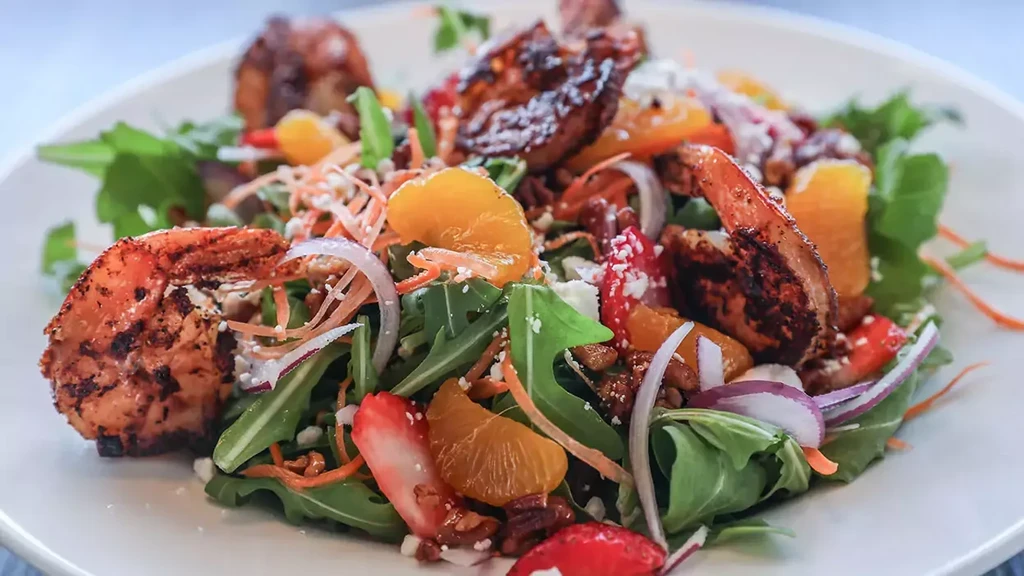Vibrant salad with grilled shrimp, oranges, strawberries, feta, and pecans.
