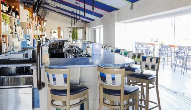 Modern bar interior with blue and white striped ceiling and counter.
