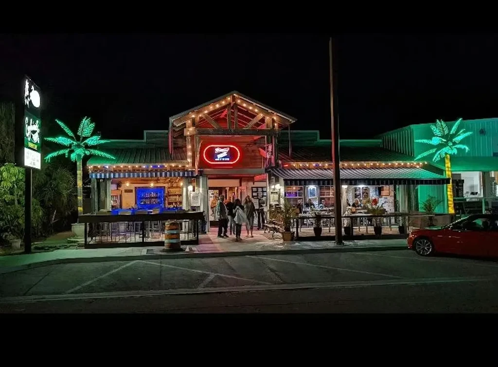 Lively '7 SEAS' restaurant exterior at night with neon sign and palm trees.