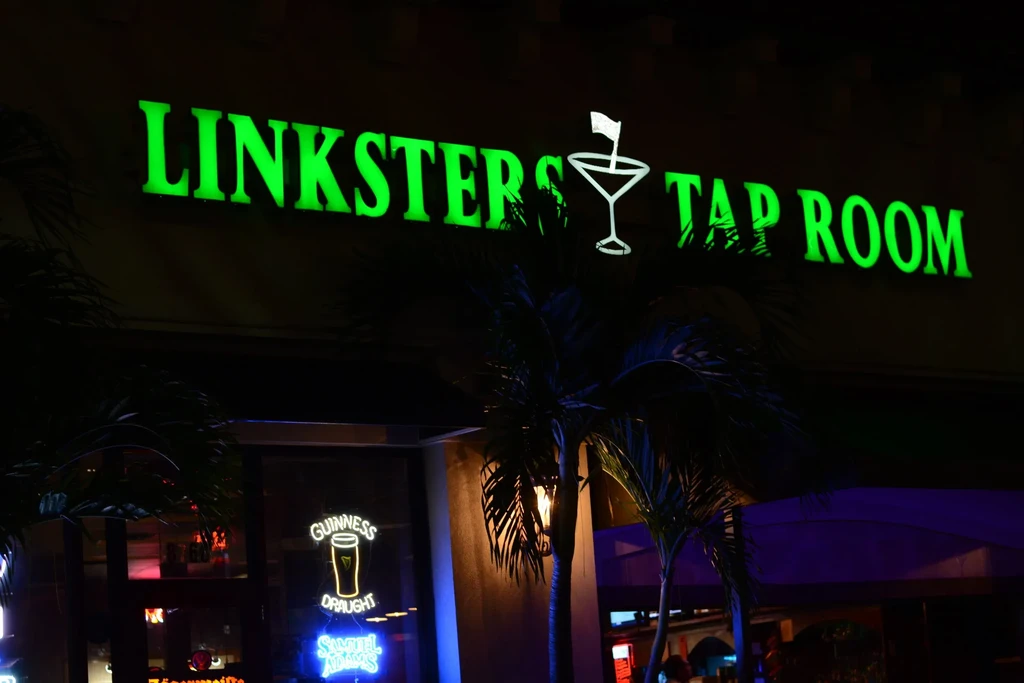 Linksters Tap Room's green neon sign, Guinness, and Samuel Adams at night.