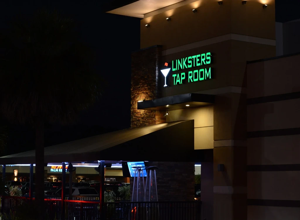 Modern Linksters Tap Room building at night, with glowing neon sign.