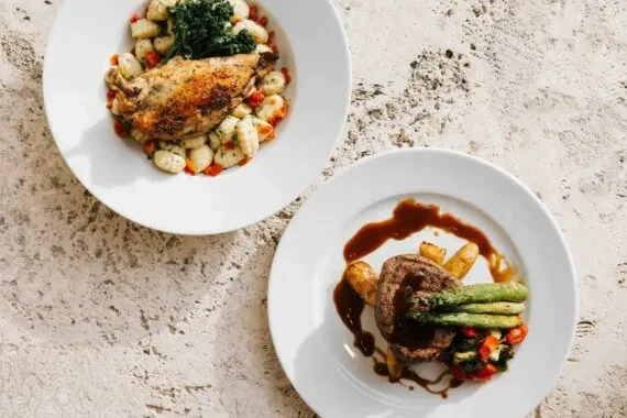 Two exquisitely plated dishes: roasted poultry with gnocchi, and steak with potatoes.