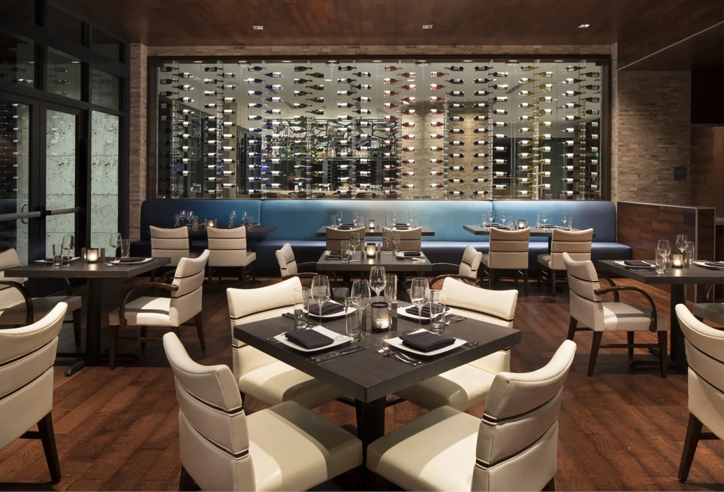 Elegant restaurant interior featuring dining tables and a prominent glass wine wall.
