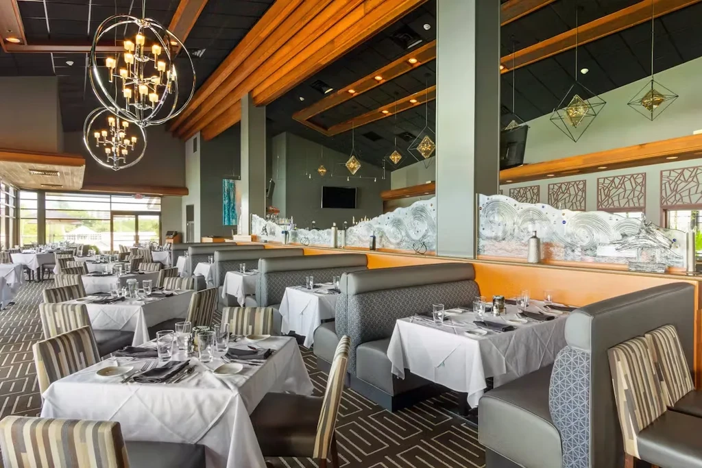 Empty upscale restaurant dining room with set tables and modern decor.