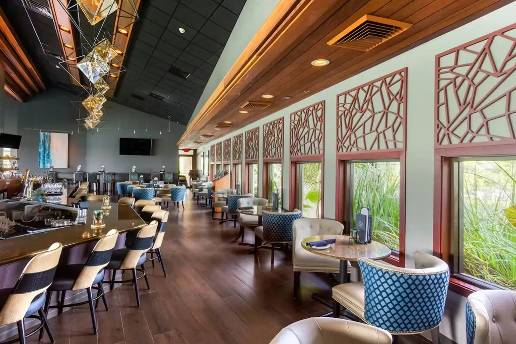 Spacious, modern restaurant interior with a long bar, dining, and green views.