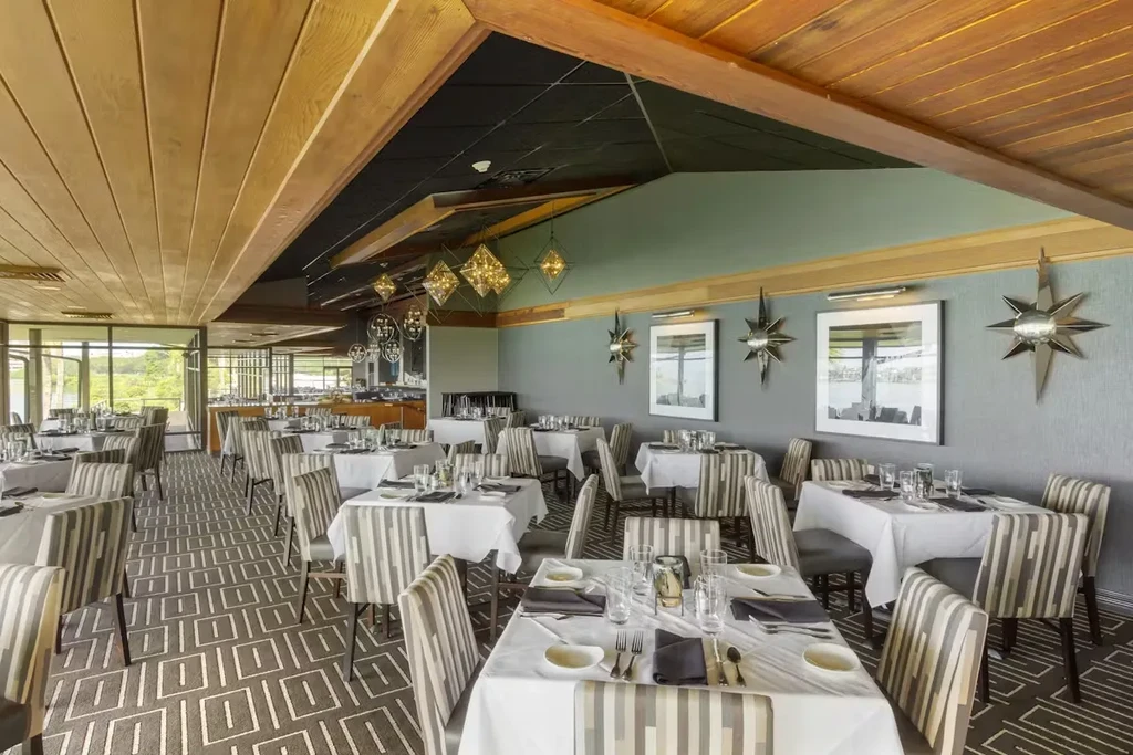 Empty elegant restaurant dining room with modern decor and nature view.