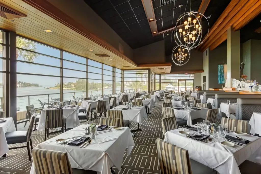 Elegant fine dining restaurant with set tables and panoramic waterfront views.
