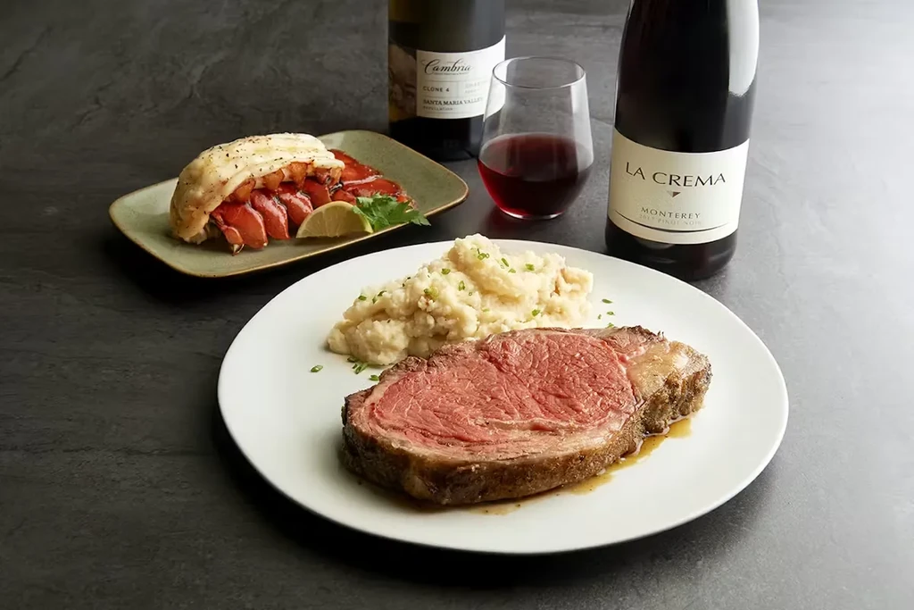 A medium-rare prime rib, lobster tail, mashed potatoes, and red wine.