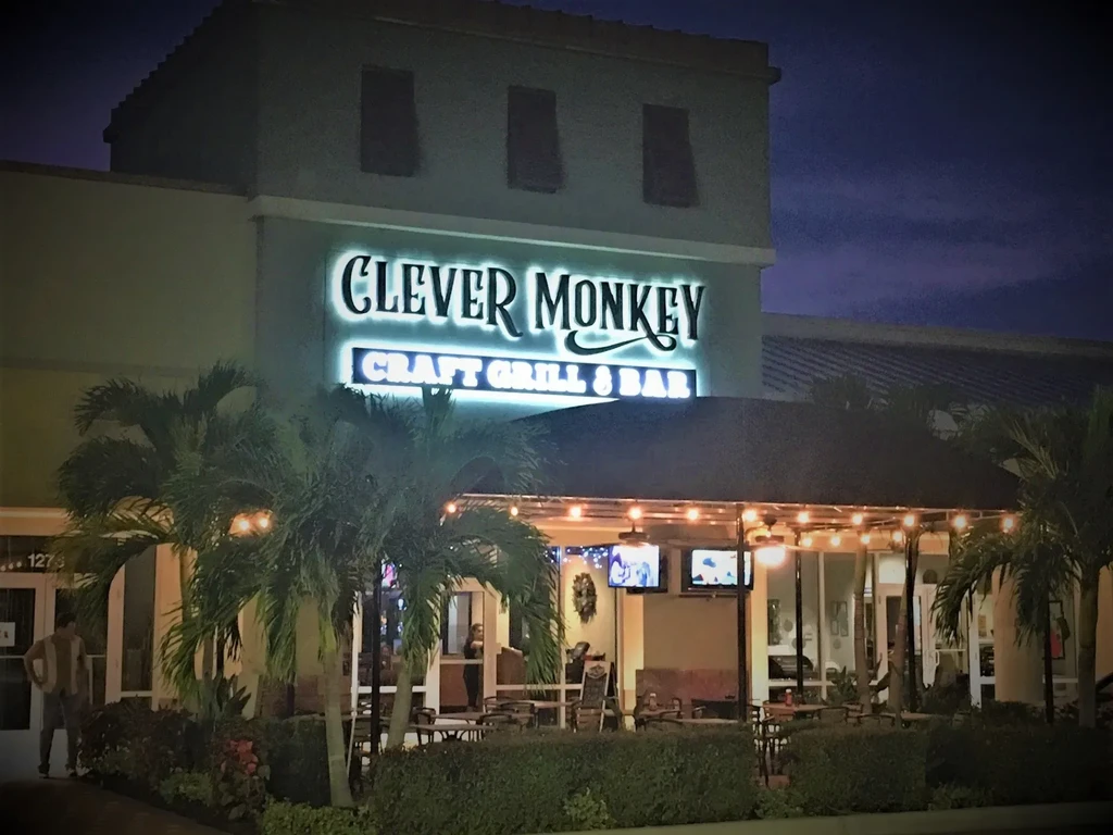 Modern Clever Monkey Craft Grill & Bar exterior at dusk, lit patio.