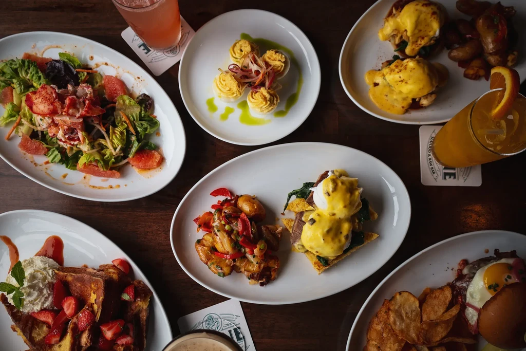 Overhead view of various breakfast and brunch dishes and drinks on a table.