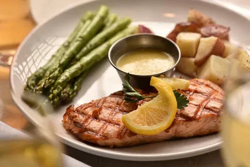 Grilled salmon, vibrant asparagus, roasted potatoes, and creamy sauce.