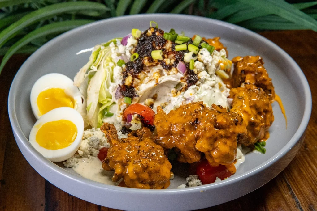 A colorful loaded wedge salad with buffalo chicken and hard-boiled eggs.
