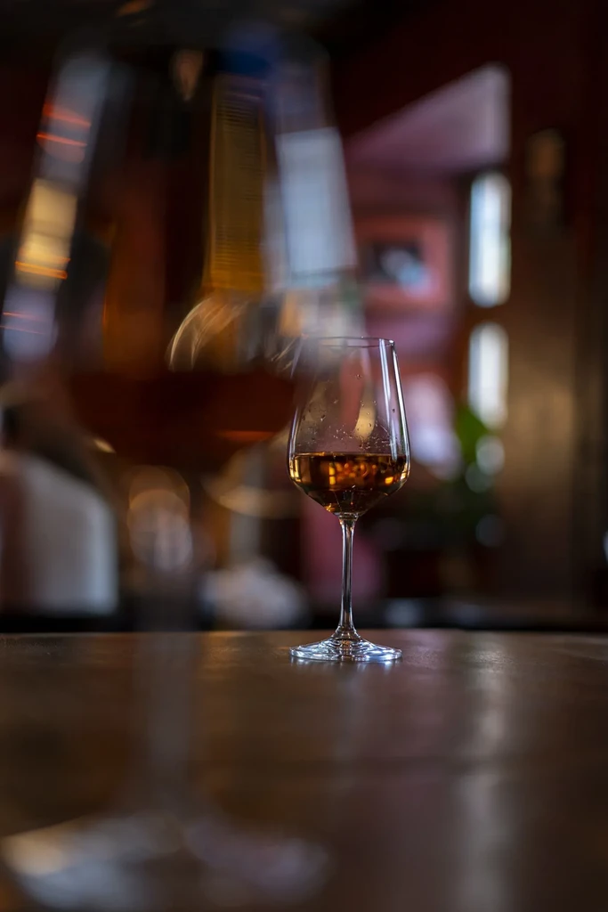 Close-up: glass with amber liquid on a dark wooden table.