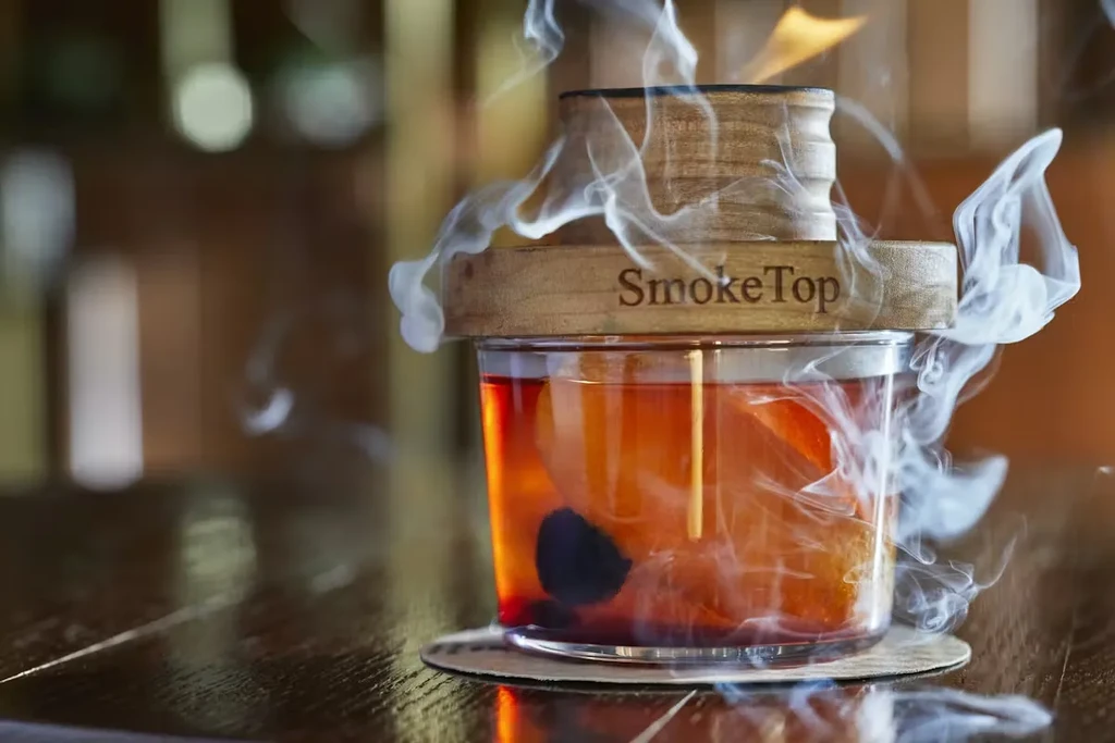Close-up of a smoking cocktail with fruit and a SmokeTop device.