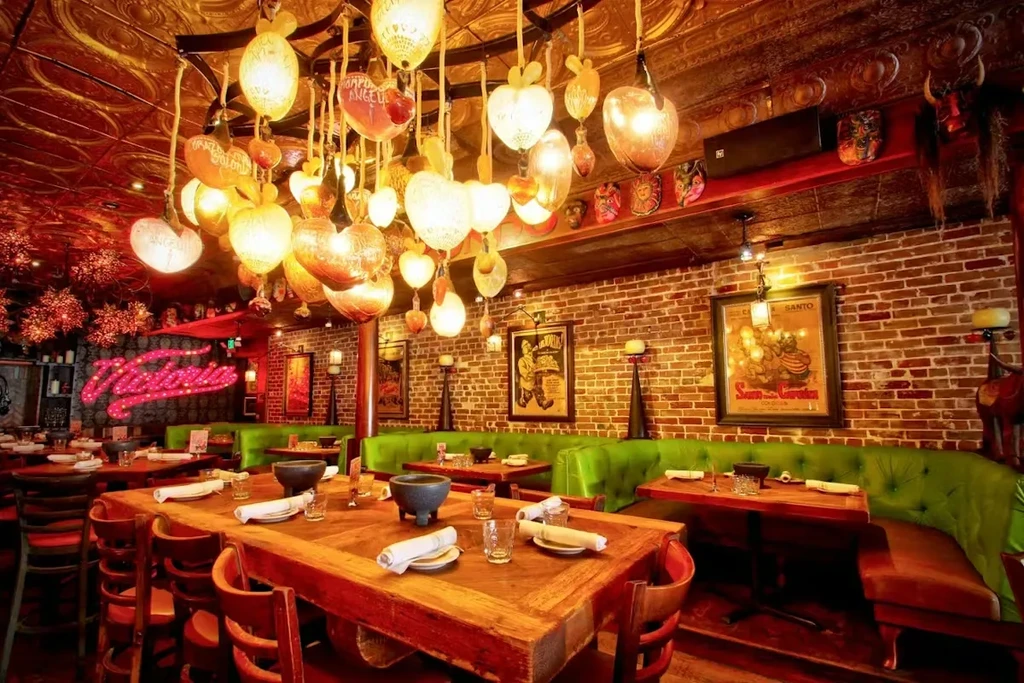 Ornate restaurant dining room with pressed tin ceiling and green velvet banquette.