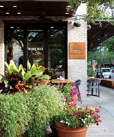 Boca Wine Bar exterior with lush plants and outdoor seating.
