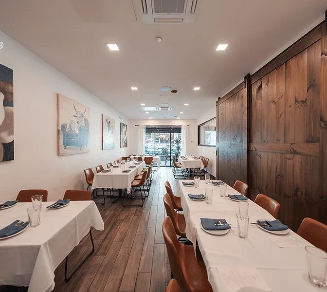Empty modern rustic restaurant dining room with white tables and unique animal art.