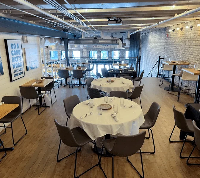 Spacious, modern restaurant interior with industrial ceiling and empty dining tables.