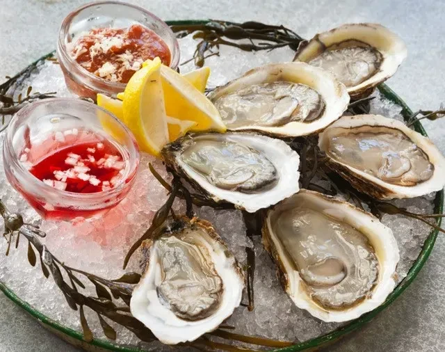 Six raw oysters on crushed ice with lemon and sauces.
