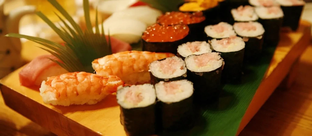 Assorted sushi, including tuna, shrimp, and roe, on a wooden board.